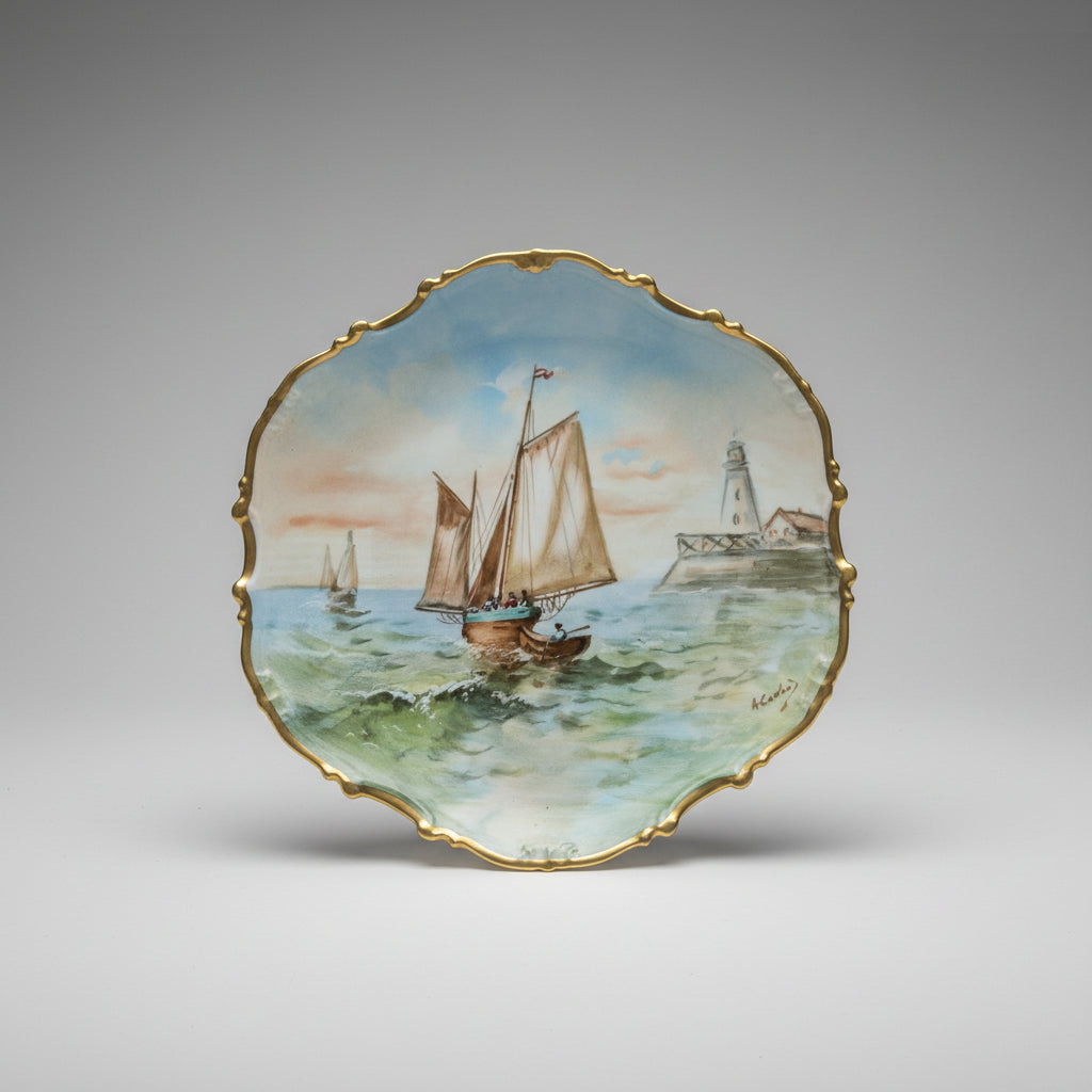A scalloped ceramic plate with a gold-trimmed edge, featuring a hand painted nautical scene of sailboats on green-blue water under a pale sky.